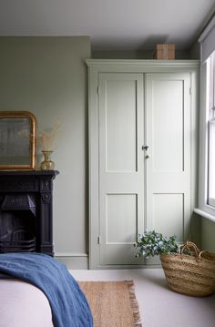 a bedroom with an armoire, bed and basket on the floor next to it