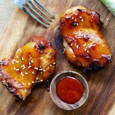 two pieces of chicken sitting on top of a wooden cutting board with ketchup