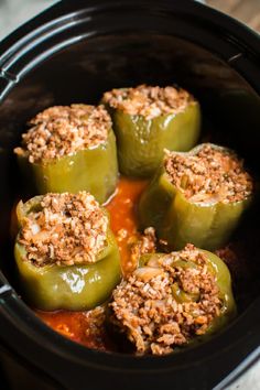 green peppers stuffed with meat and cheese in a baking pan on the stove burner