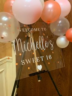 a welcome sign with balloons and confetti in the background on a tripod