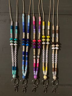 several different colored beads and keychains hanging from hooks on a black surface with two pairs of scissors