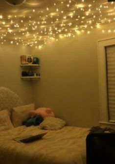 there is a bed with lights hanging from the ceiling and a laptop on top of it