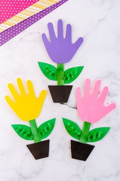 four handprinted flowers sitting on top of a marble table next to a pink and yellow flower pot