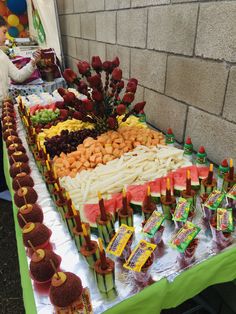 an assortment of fruits and vegetables are on display at a buffet table in front of a brick wall