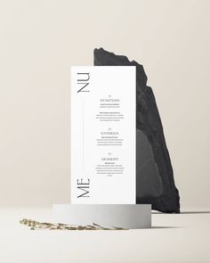 a black and white wedding card on top of a table next to a stone mountain