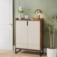 a white cabinet sitting next to a potted plant