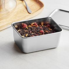 a metal container filled with food next to a wooden cutting board