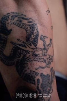 a close up of a person's arm with a dragon tattoo on the side