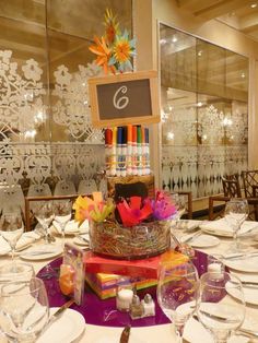 the table is set up for a celebration with colorful decorations and place settings on it