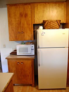 a white refrigerator freezer sitting inside of a kitchen next to wooden cupboards and counter tops