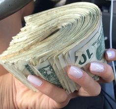 a woman holding money in her hand while sitting in the back seat of a car