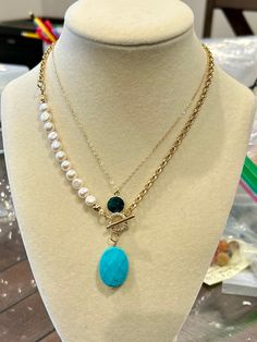 This stylish and elegant necklace effortlessly blends the timeless allure of pearls with the sleek sophistication of a gold chain. The addition of a large natural turquoise pendant adds a unique, eye-catching element that elevates its charm. Perfect for both everyday wear and special occasions, this necklace is a versatile accessory that enhances any fashionable outfit. **Description** * Rolo Chain: 14K gold plated on brass * Freshwater pearls, 6~7mm, button shaped * Gemstone turquoise pendant, Elegant Turquoise Chain Necklace Gift, Elegant Double Strand Turquoise Necklace, Elegant Turquoise Pearl Necklace, Turquoise Pearl Necklace With Pearl Drop, Turquoise Necklace With Pearl Drop As Gift, Gift Turquoise Necklaces With Pearl Chain, Turquoise Necklace With Pearl Drop For Gift, Elegant Turquoise Pearl Drop Necklace, Elegant Turquoise Necklace With Pearl Chain