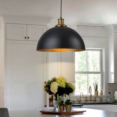 a kitchen island with flowers in vases on it and an overhead light hanging from the ceiling