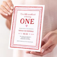 a woman holding up a birthday card with the number one on it