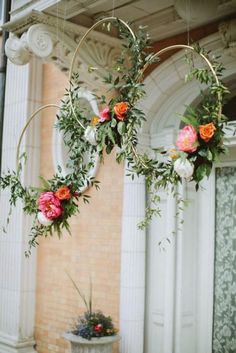 two hoop hanging from the ceiling with flowers and greenery on it's sides