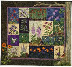 a quilted wall hanging with flowers and butterflies on it's side, in front of a tree