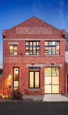 an old brick building with glass doors and windows on the front door is lit up at night