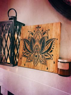 a wooden sign with a flower on it next to a candle