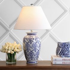 a blue and white vase sitting on top of a wooden table next to a lamp