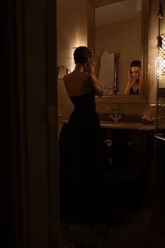 a woman standing in front of a bathroom mirror