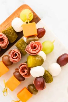 grapes, apples, cheese and crackers are arranged on a white plate with a cutting board