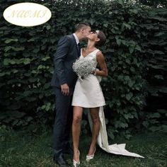 a bride and groom kissing in front of a hedge with the words macom on it