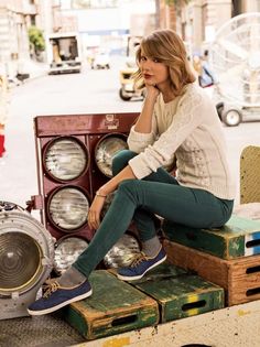 a woman sitting on top of a pile of junk next to an old washer