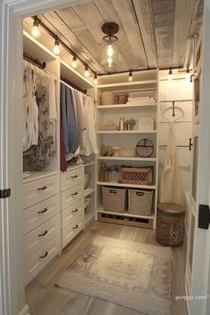 a walk in closet with lots of drawers and hanging lights on the ceiling above it