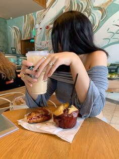 a woman sitting at a table with a cup of coffee and some food in front of her