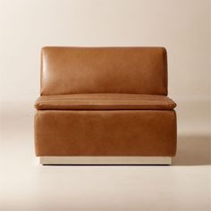 a brown leather chair sitting on top of a white floor next to a beige wall