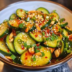 a bowl filled with sliced cucumbers and sesame seeds on top of a table