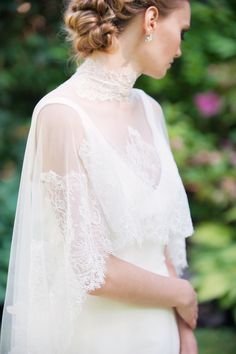 a woman wearing a white wedding dress with a veil on her head and hair in a bun