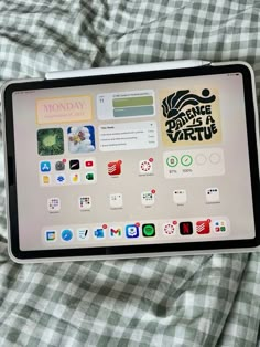 an ipad sitting on top of a bed covered in plaid sheets with stickers all over it