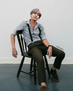 a young man sitting in a chair wearing suspenders and a button - down shirt