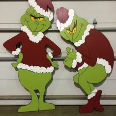 two green cartoon characters standing next to each other in front of a white garage door