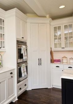 a kitchen with white cabinets and wood floors