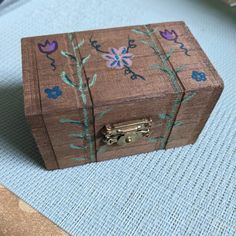 a small wooden box with flowers painted on the outside and inside, sitting on a blue surface