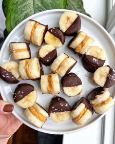 a white plate topped with chocolate covered bananas and half peeled banana's on top