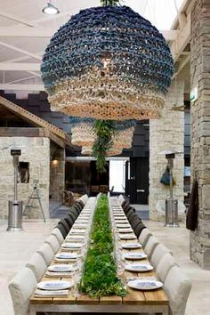 a long table with many plates and silverware on it is surrounded by large chandeliers