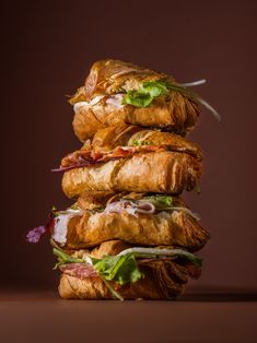 a stack of croissant sandwiches sitting on top of each other in front of a brown background