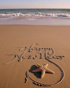 a happy new year written in the sand with a starfish