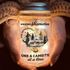 a person holding a mason jar that says making memories one a campsite at a time