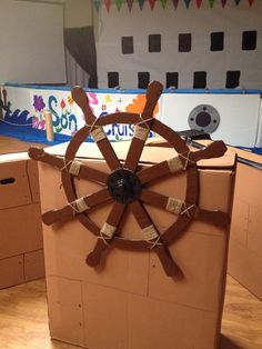 a cardboard box with a steering wheel on the inside and roped around it's sides