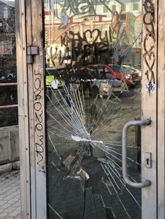 a broken glass door with graffiti on it