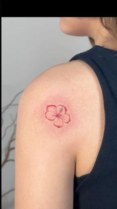 a woman's shoulder with a flower tattoo on the left side of her arm