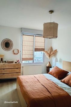 a bed sitting in a bedroom next to a window covered in orange sheets and pillows