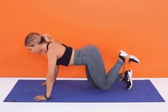 a woman in grey pants and black top doing a push up on a blue mat