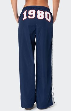 These Edikted 1980 Nylon Track Pants offer both style and comfort, making them perfect for a sporty yet fashionable look. They're ideal for any activity, ensuring you feel comfortable and confident throughout your entire day. Track pantsLace stripe detailingSlitted hemAdjustable waist tieEmbroidered graphic textPolyesterModel wears size SModel height is 5'8Item care: Machine wash at maximum 30C, wash with similar colors, do not bleach, do not tumble dry, iron at a maximum of 110C, do not dry clean. Edikted Womens 1980 Nylon Track Pants - Blue size XS Sweatpants With Words On Back, Sporty Fits, Cool Sweatpants, White Track Pants, Nylon Track Pants, Vintage Sweatpants, Graphic Sweatpants, Hip Hop Pants, Birthday Fits