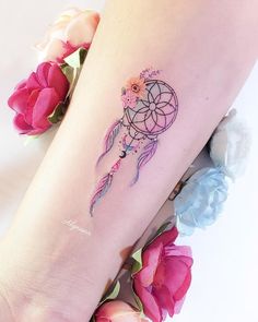 a woman's leg with a tattoo on it that has a dream catcher and flowers