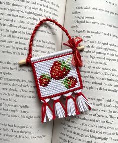 an open book with a red and white cross - stitch ornament on it